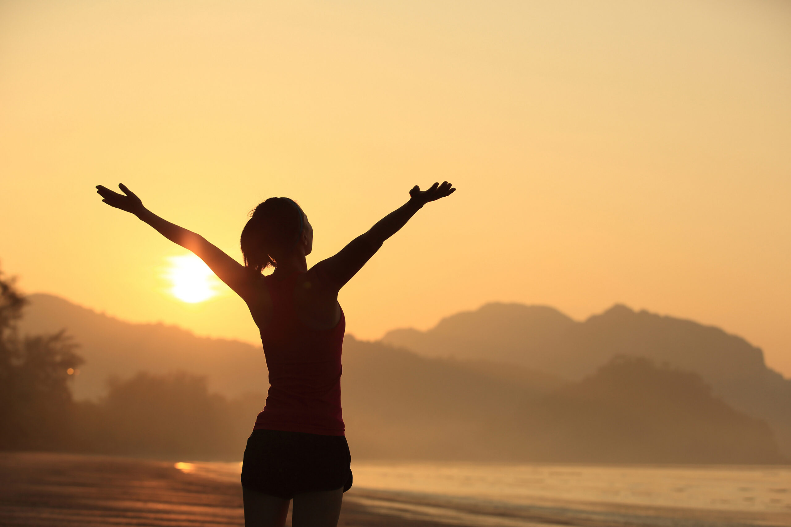 Silhouette einer Frau am Strand bei Sonnenaufgang
